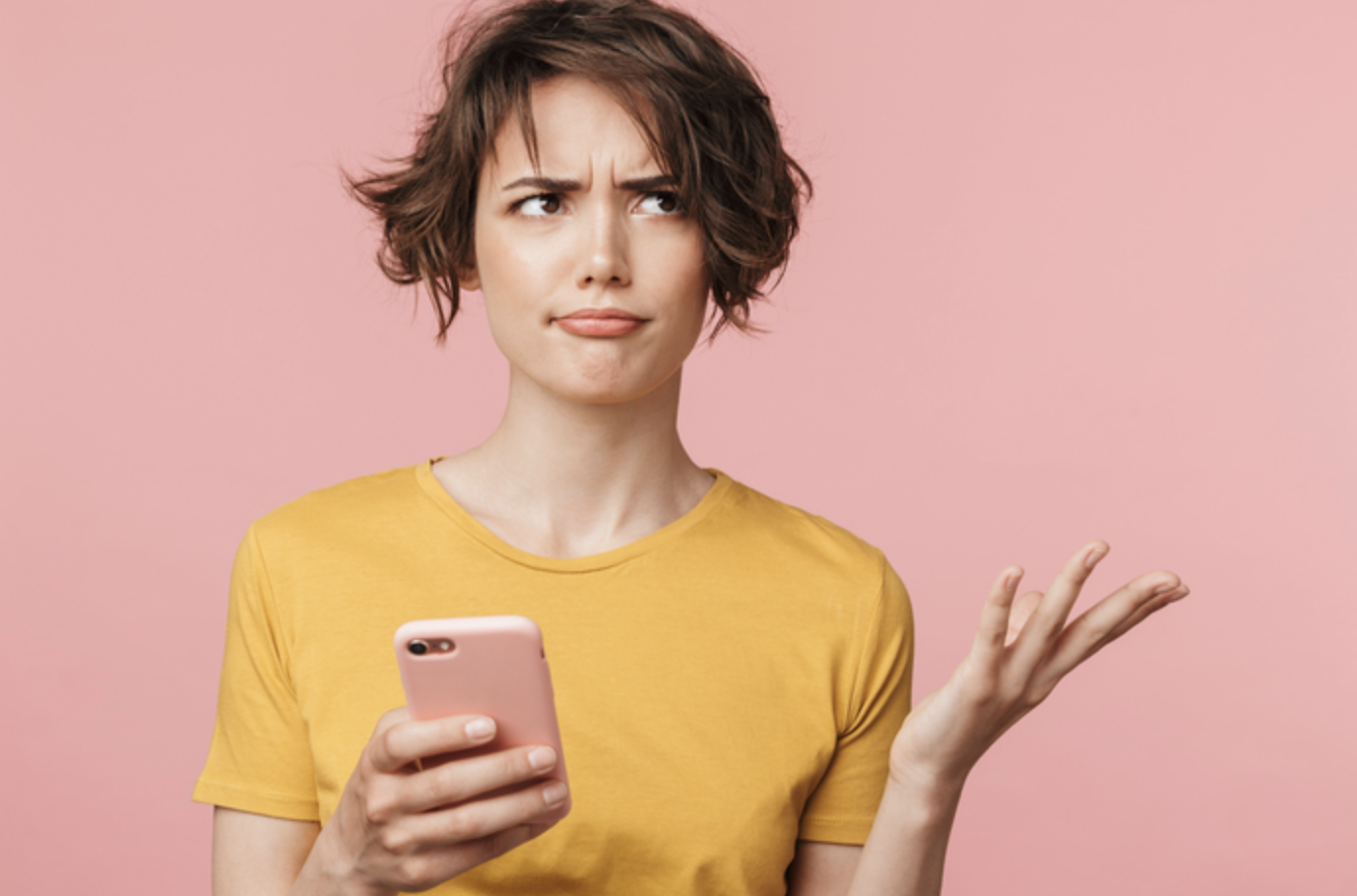 a person holding a smartphone and expressing confusion