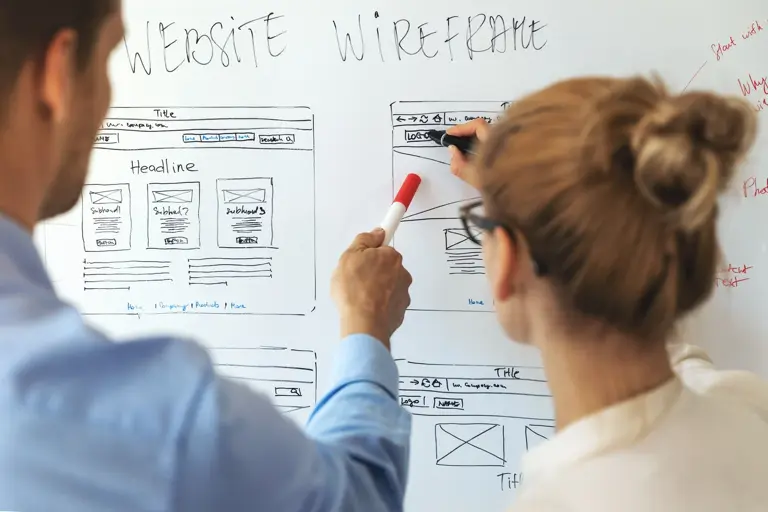 two people reviewing work on a whiteboard