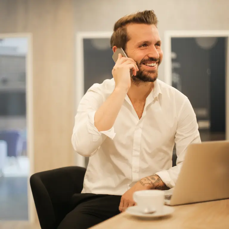 man on mobile phone while working on laptop