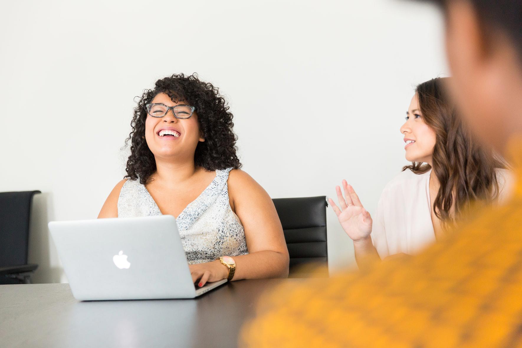 person laughing using a laptop