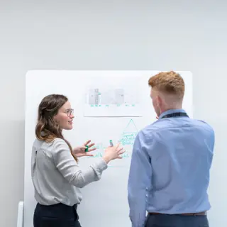 two people having a discussion near a whiteboard