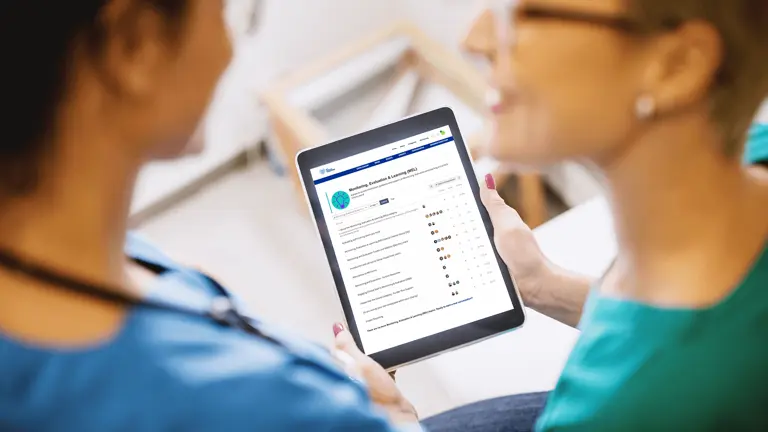 Two medical professionals reviewing important best practice information on tablet 