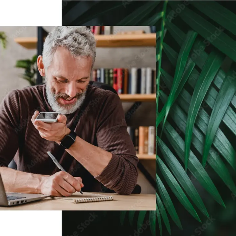 A man on the phone with his bank making notes on paper