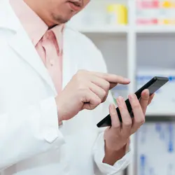 A pharmacist reviewing important guidance using their mobile phone