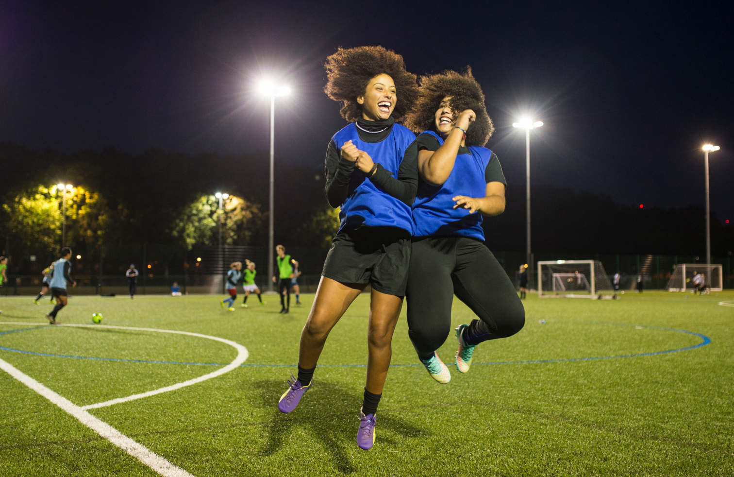 Two young women celebrating on a football field